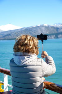 Rear view of woman photographing sea against sky