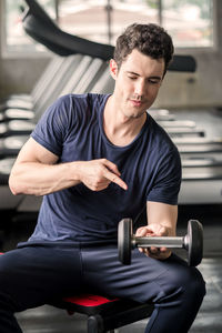 Lifestyle playful man having fun lifting dumbbell in gym exercise with work out program for healthy.