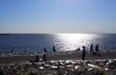 People on beach against clear sky