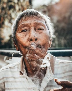 Close-up portrait of man smoking cigarette outdoors