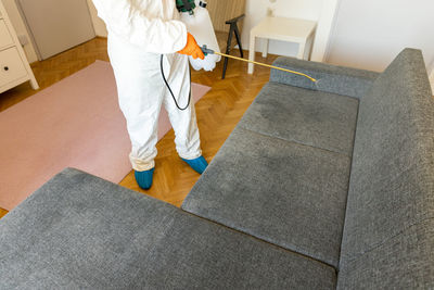 Low section of man standing on sofa at home