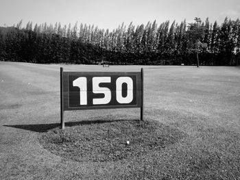 Information sign on field against sky