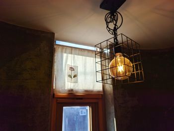 Low angle view of illuminated pendant light hanging in building