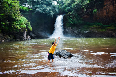 Full length of boy surfing on waterfall