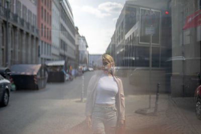 Double exposure of beautiful young woman walking in front of buildings on 