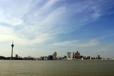 Sea by cityscape against sky