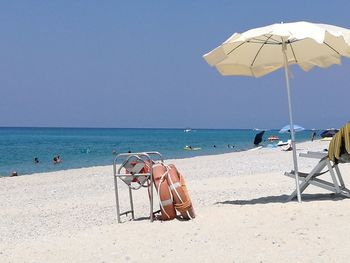 Deck chairs on beach against clear blue sky