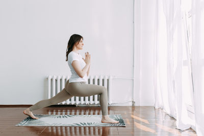 Side view of woman sitting on hardwood floor