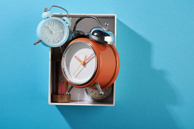 High angle view of clock on table against blue wall