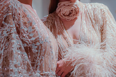 Fashion details of pastel pink haute couture boudoir dresses and a rose accessory around the neck