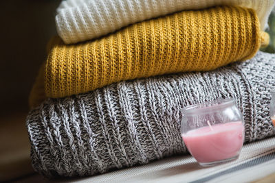 Close-up of tea light candle by stacked sweaters on table