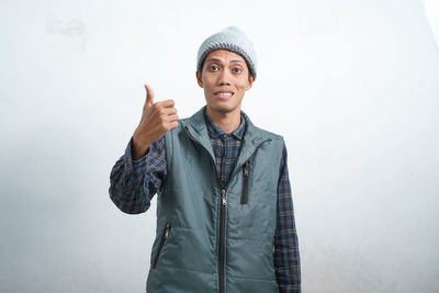 Portrait of young man standing against wall