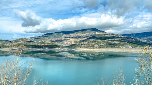 Scenic view of lake by mountains against sky