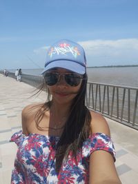 Portrait of woman wearing sunglasses against sea