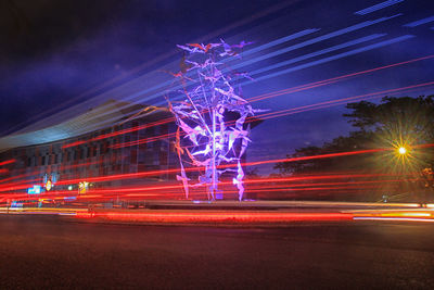 Light trails on road against sky at night