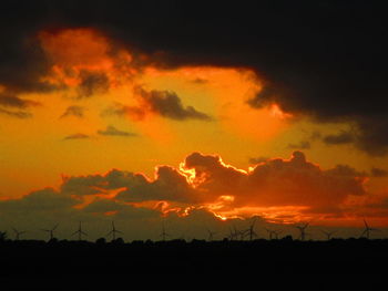 Silhouette landscape against dramatic sky during sunset