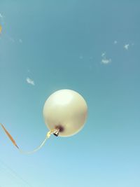 Low angle view of helium balloons against blue sky