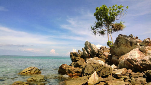 Scenic view of rocks by sea against sky