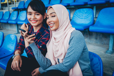 Young woman using phone while sitting on laptop