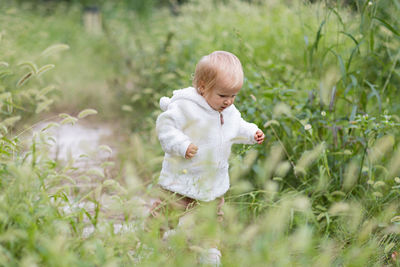 Portrait of cute girl with arms raised standing on field