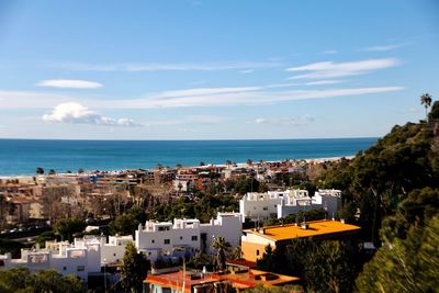 High angle view of townscape by sea against sky