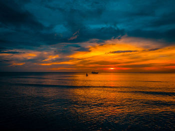 Scenic view of sea against dramatic sky during sunset