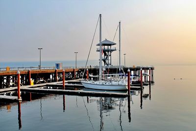 Ship moored at harbor against sky during sunset