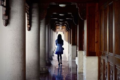Rear view of woman walking in corridor of building