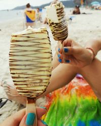 Close-up of women hands holding frozen sweet food at beach