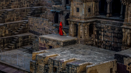 Woman holding broom while standing on historic building