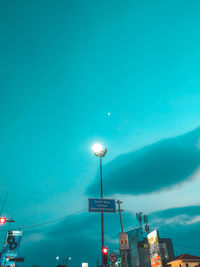 Low angle view of illuminated street lights against blue sky