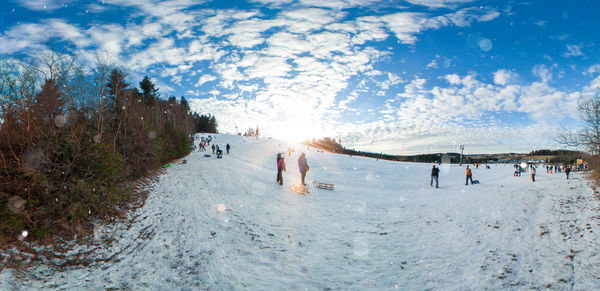 Tourists on snow land against sky during sunny day