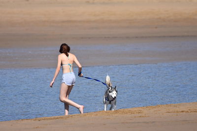 Full length of woman with dog on beach