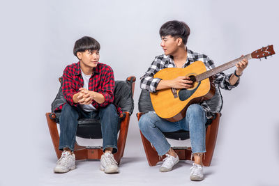 Friends sitting on floor against white background