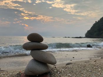 Stack of stones on beach against sky