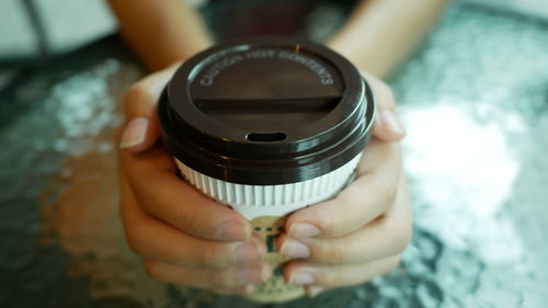 Close-up of hand holding coffee cup on table