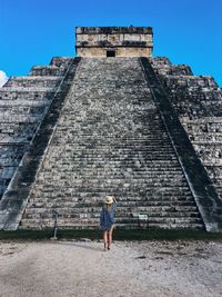 Rear view of woman standing by historical building against sky