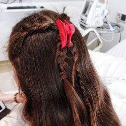 Rear view of woman with brown hair sitting in medical clinic