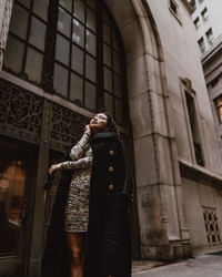 Low angle view of woman standing against building