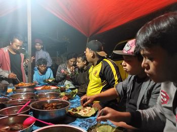 Rear view of people having food at market