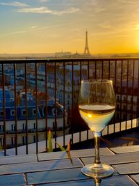 Wine glass on table against sky during sunset