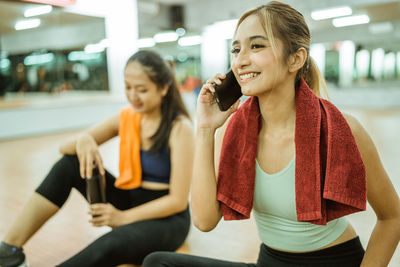Portrait of young woman using mobile phone while sitting in gym