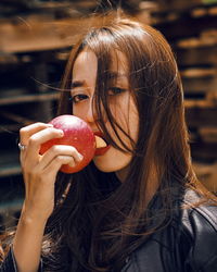 Close-up portrait of young woman eating apple