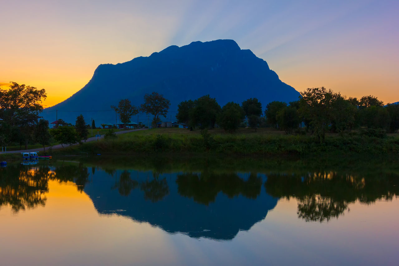 SCENIC VIEW OF LAKE BY MOUNTAINS AGAINST SKY AT SUNSET