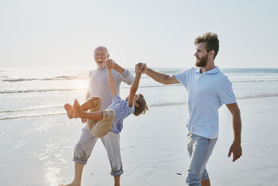 Happy grandfather, father and son on the beach