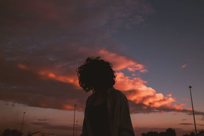 Woman standing against sky during sunset