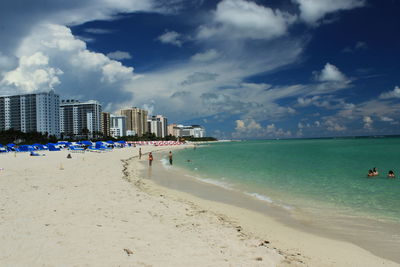 Panoramic view of people on beach against sky