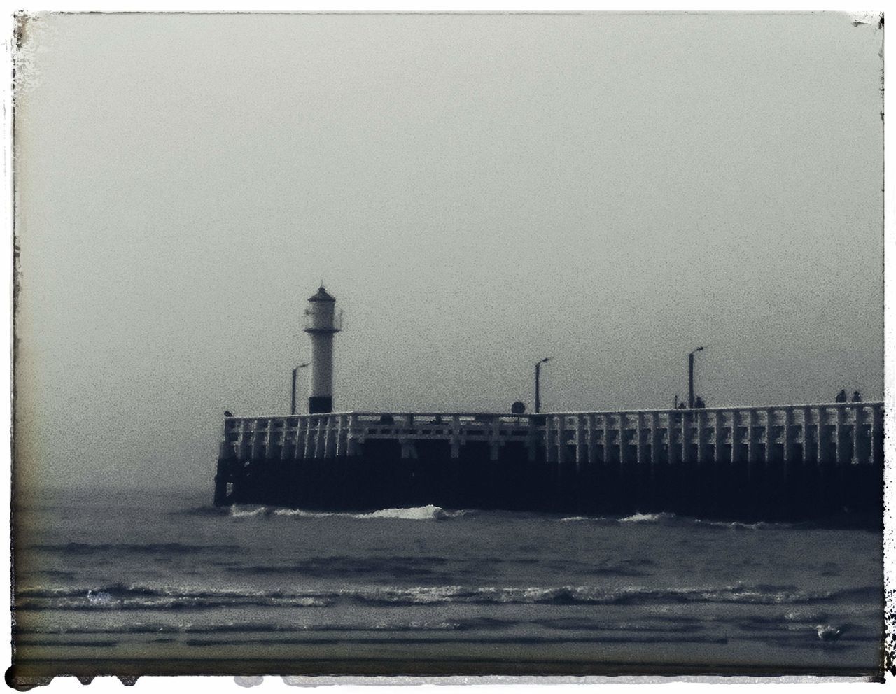 LIGHTHOUSE BY SEA AGAINST CLEAR SKY