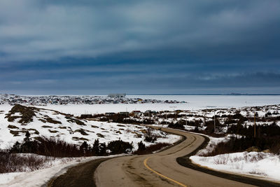 Road by snowcapped mountain against sky