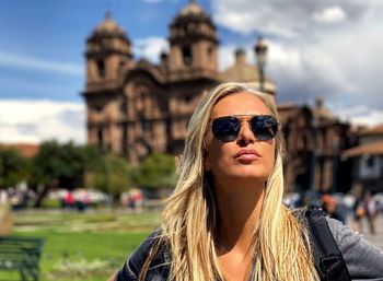 Portrait of young woman in sunglasses against built structure